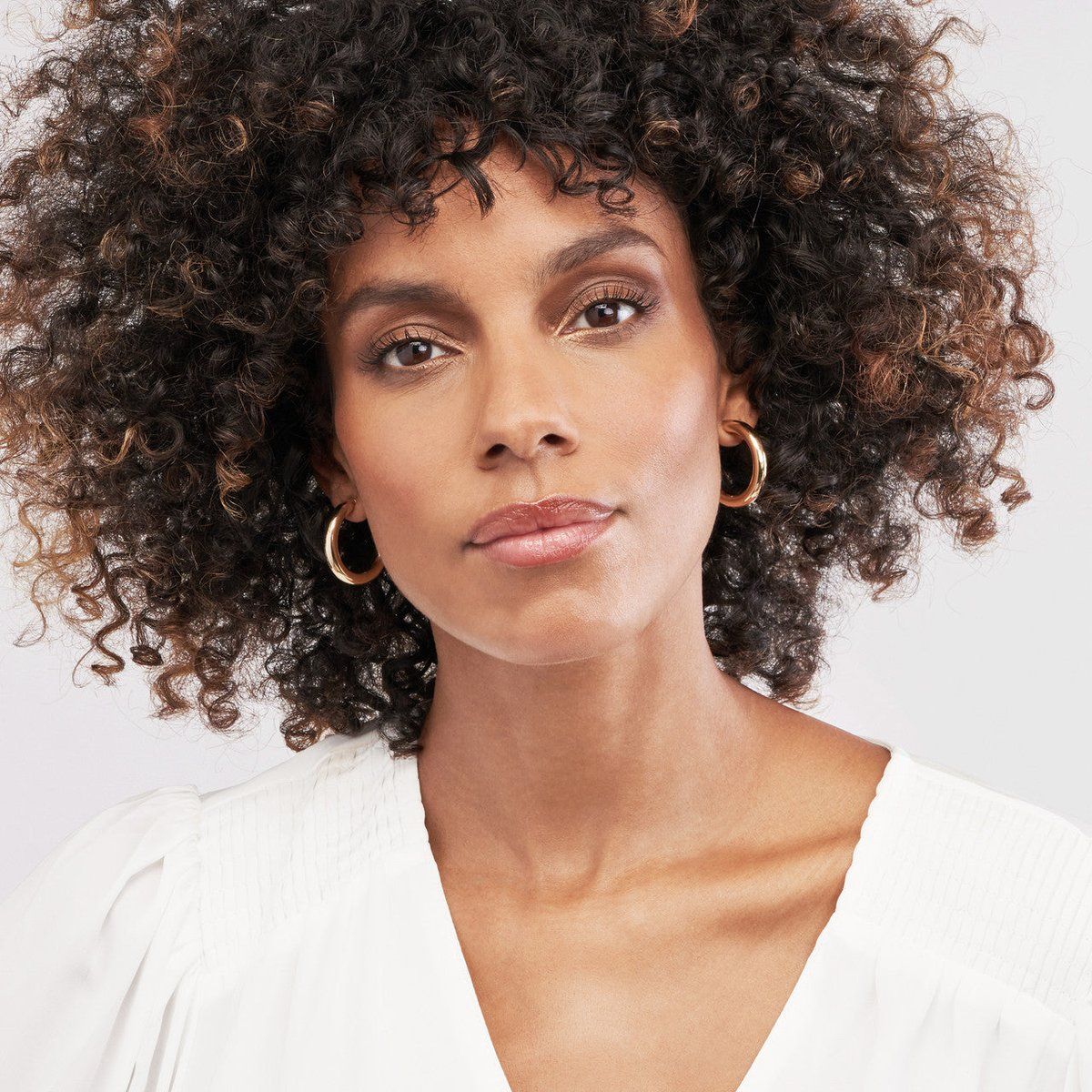 Image of a woman wearing gold hoop earrings