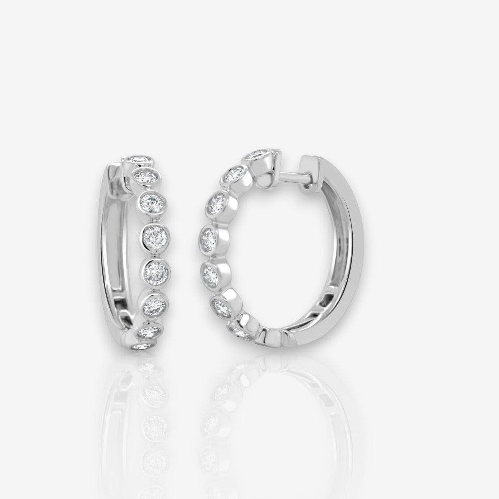 Image of bezel set diamond huggie earrings in white gold 