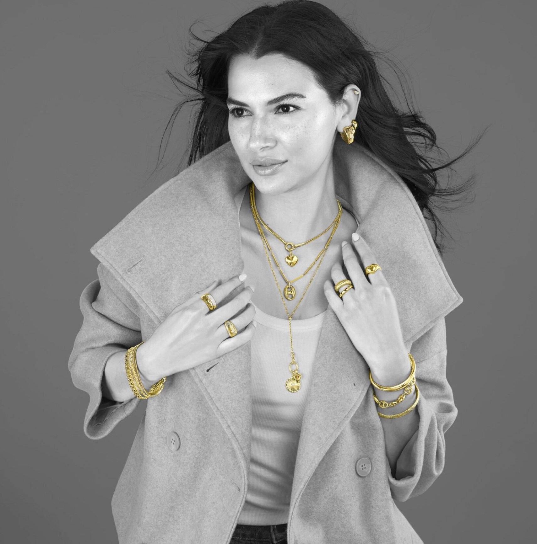 Image of woman with dark hear wearing a light wool jack and a lot of yellow gold jewlery