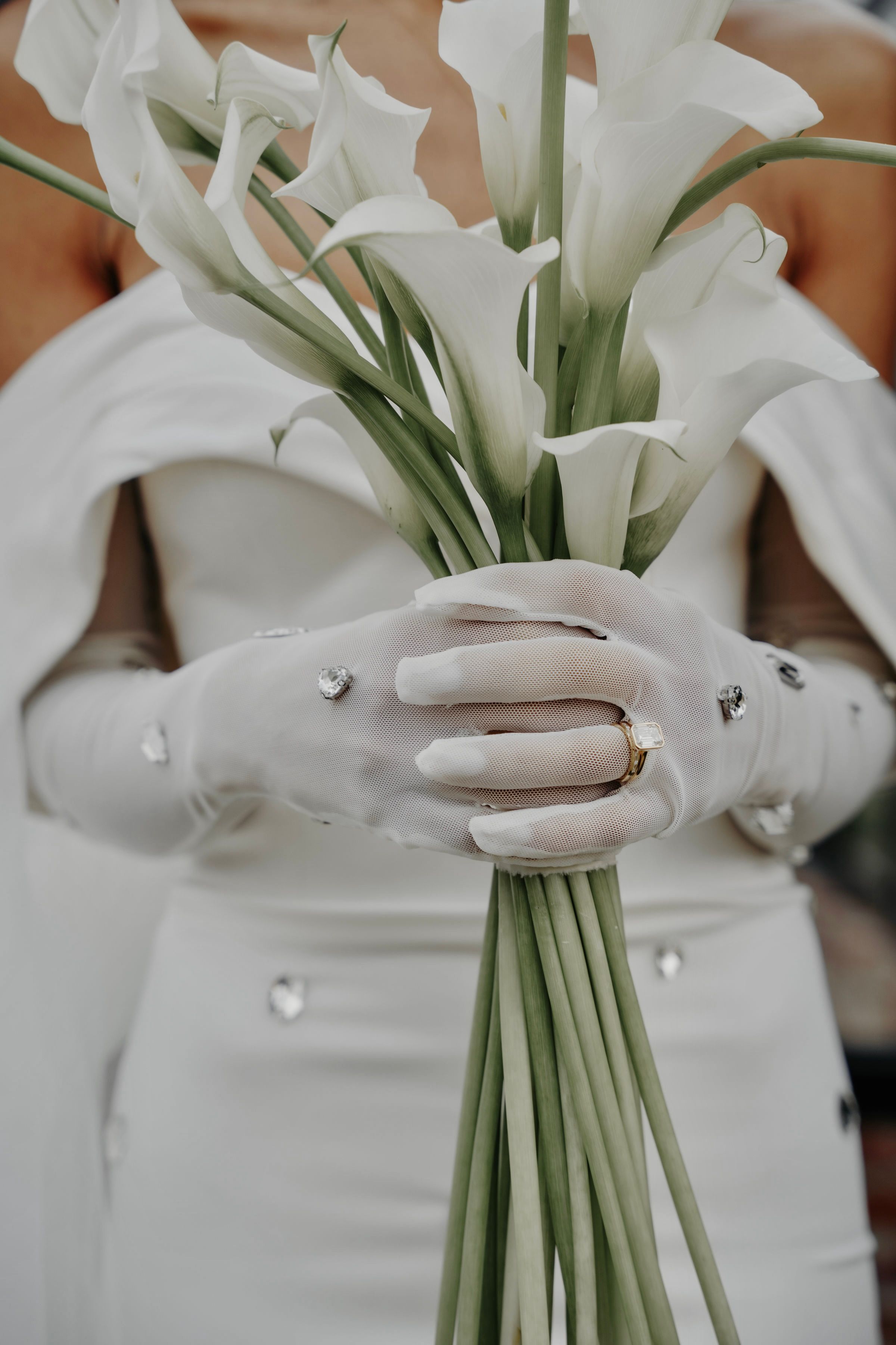 Image of woman in wedding dress embellished with crystals holding white flowers