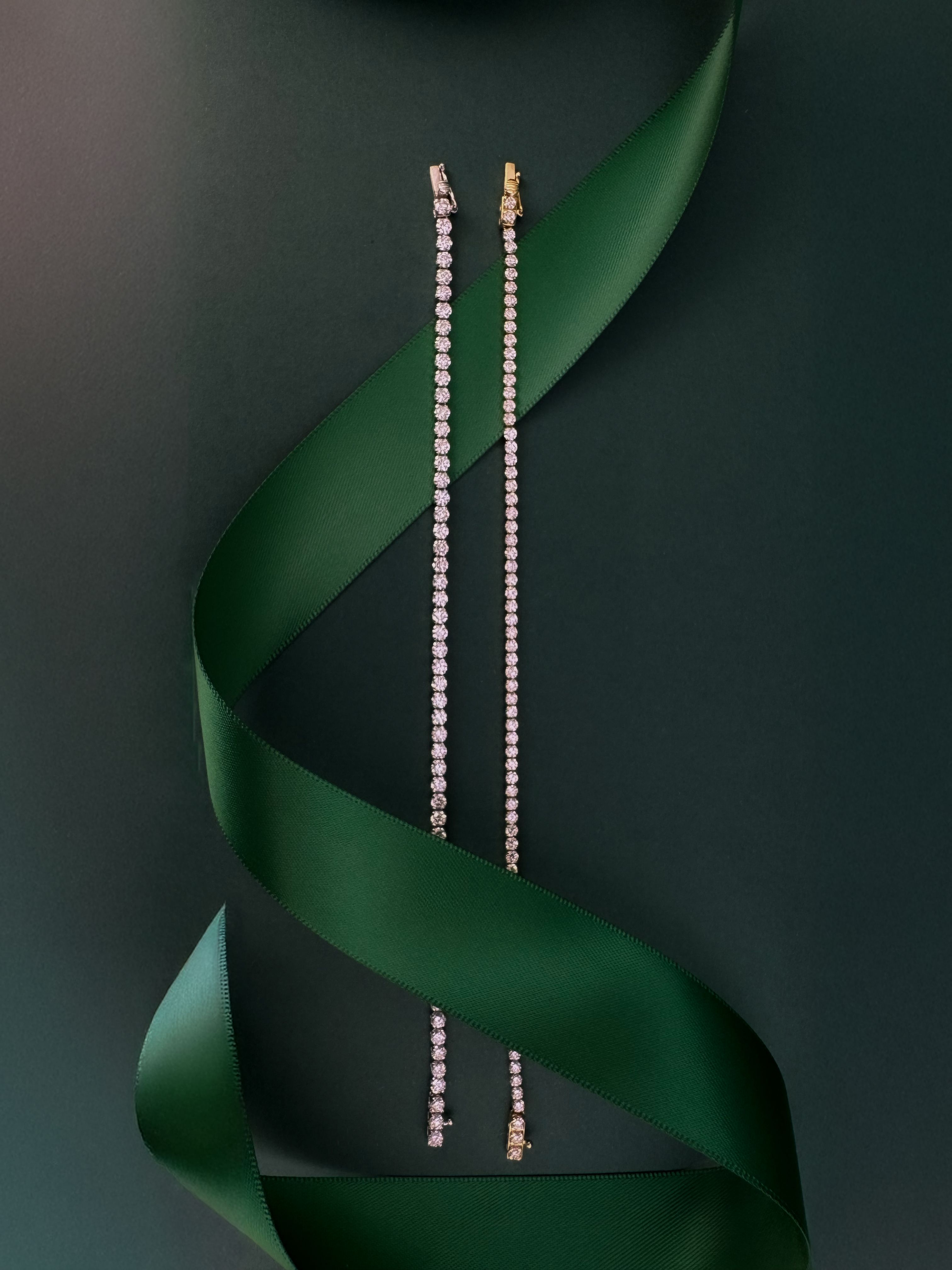 Image of two diamond tennis bracelets with dark green ribbon